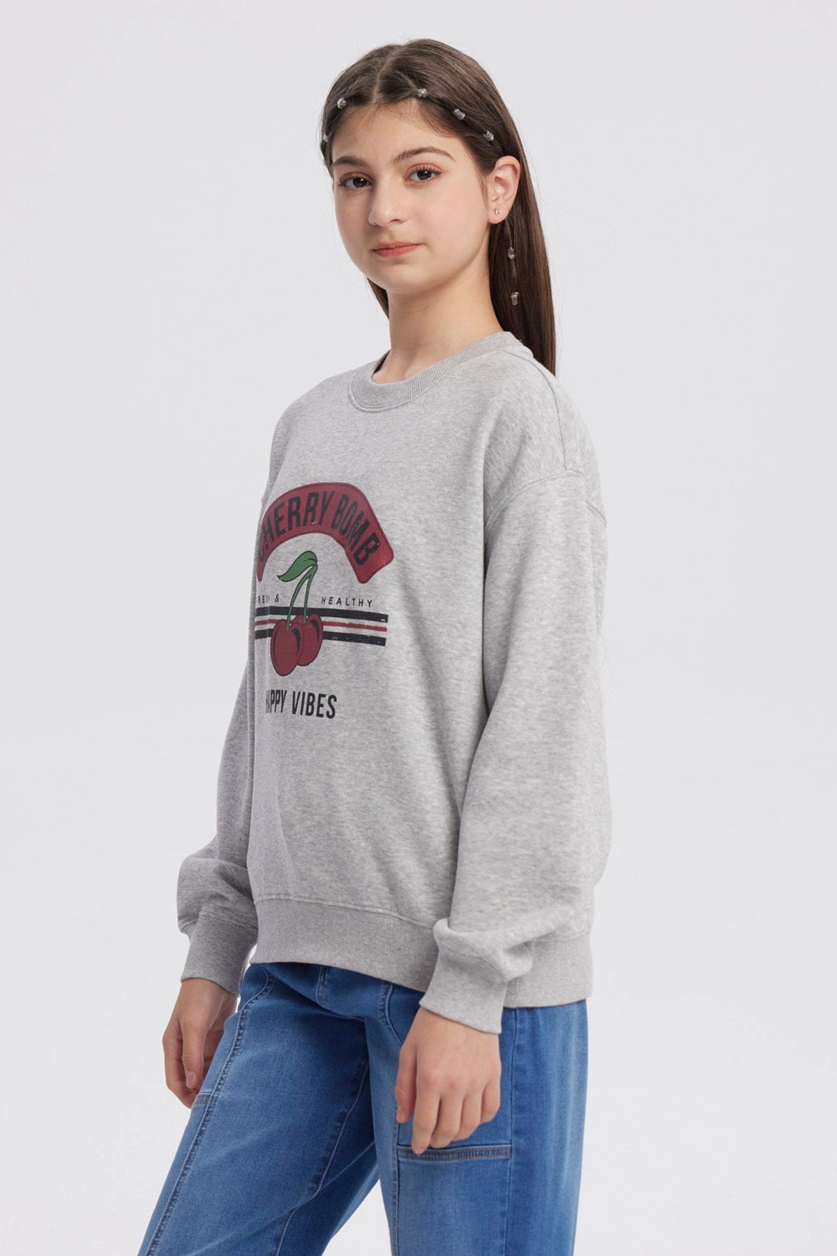 Polerón gris melange para niña con estampado Cherry Bomb en el frente mostrando cerezas y texto Happy Vibes
