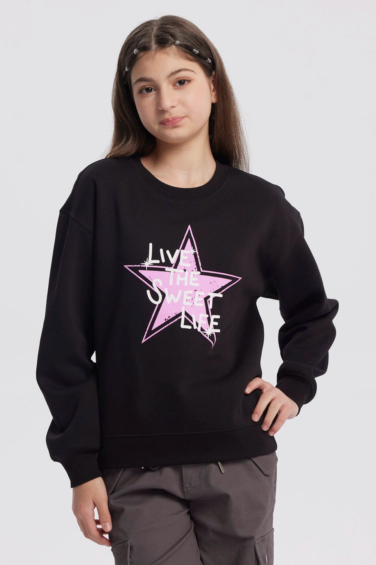 Polerón negro para niña con estampa de estrella rosa y texto Live the Sweet Life al frente en estilo gráfico moderno
