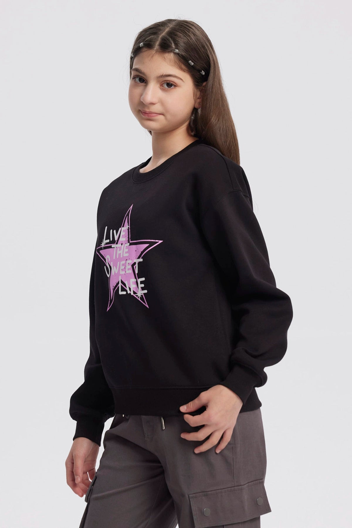 Polerón negro para niña con estampa de estrella rosa y texto Live the Sweet Life al frente en estilo gráfico moderno