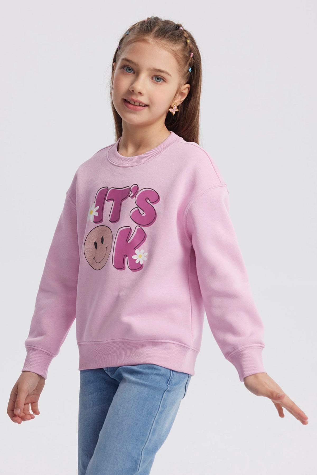 Polerón rosa para niña con diseño de "IT'S OK" en el frente letras grandes con carita feliz y flores estilo gráfico