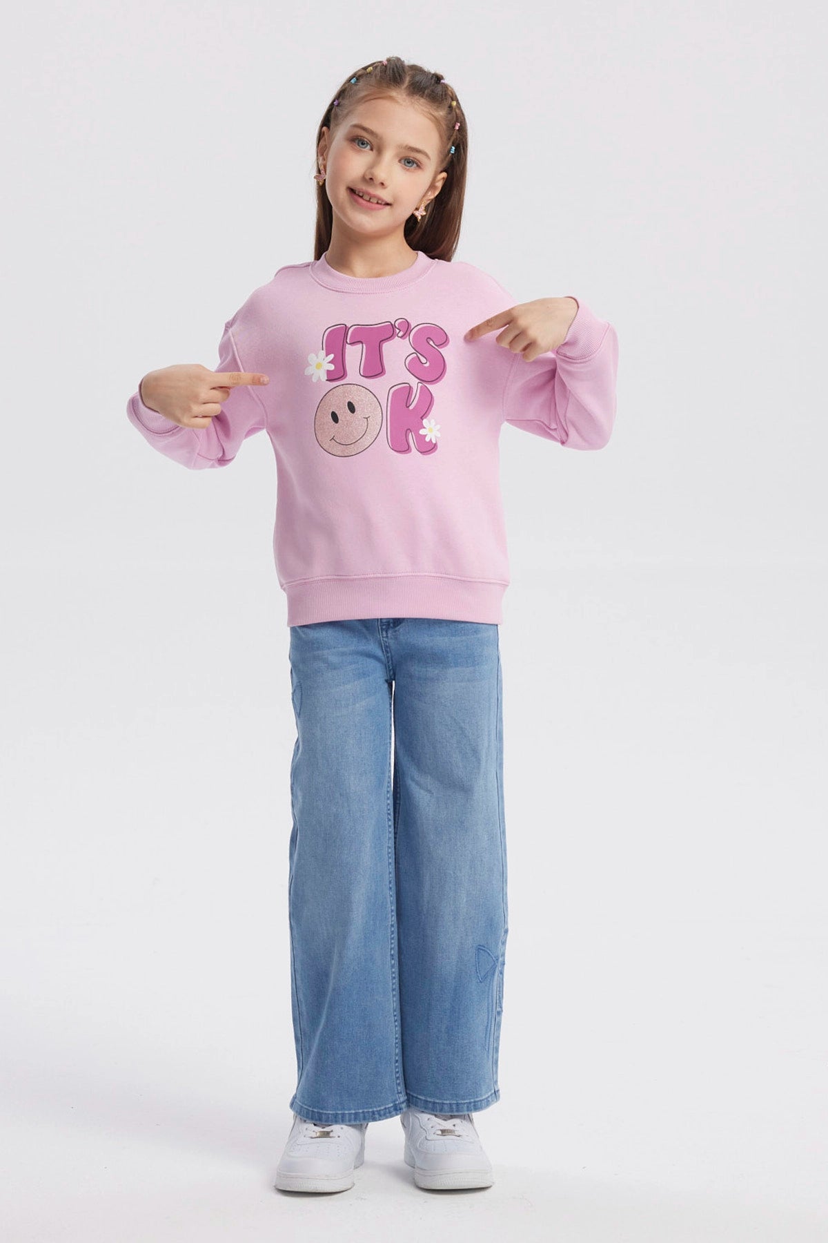 Polerón rosa para niña con diseño de "IT'S OK" en el frente letras grandes con carita feliz y flores estilo gráfico