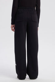 Pantalón buzo niña negro con corte wide leg líneas blancas verticales a los lados diseño deportivo y texto "active" en el tobillo