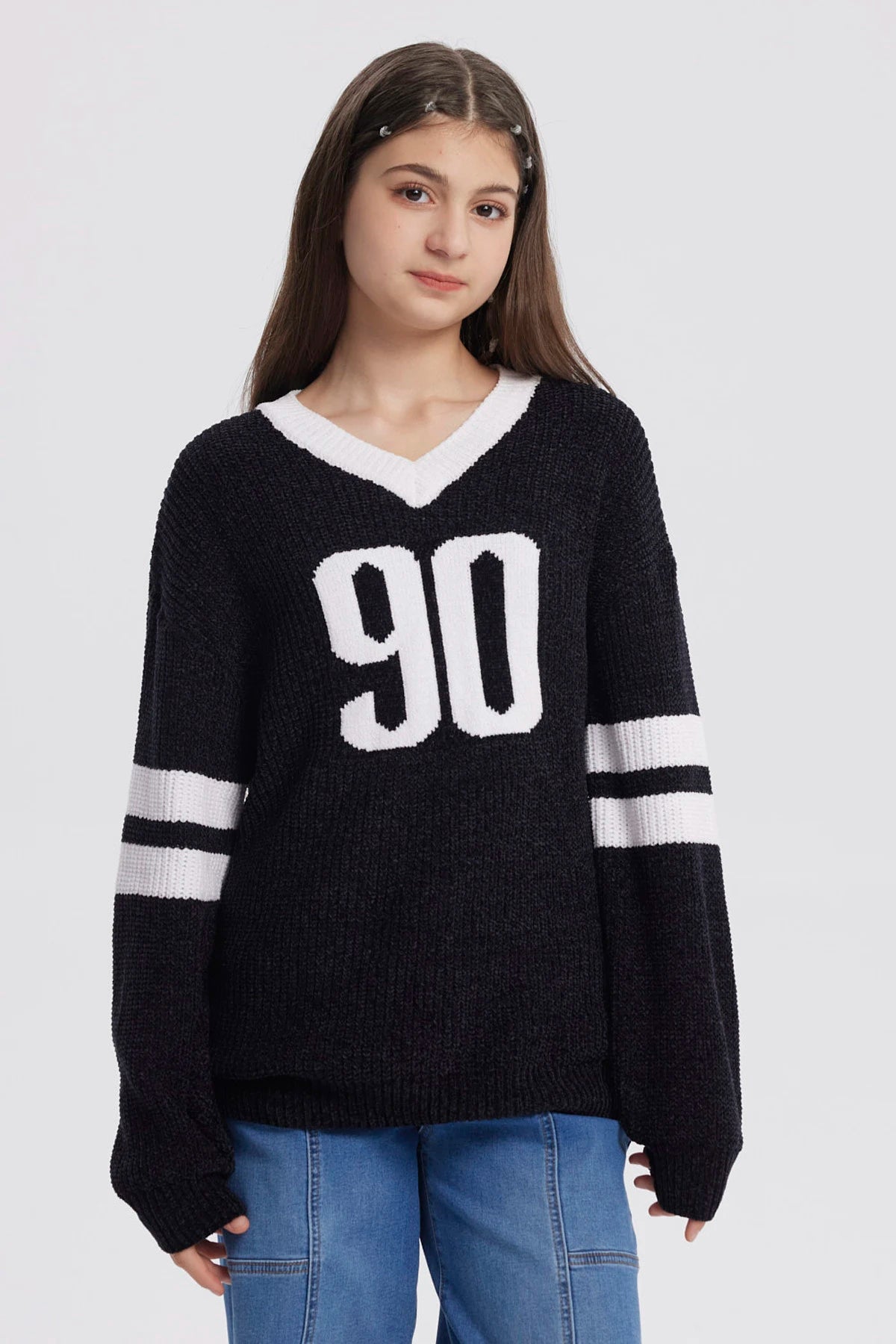 Sweater oversize negro para niña con el número 90 en blanco al frente y rayas blancas en las mangas estilo deportivo