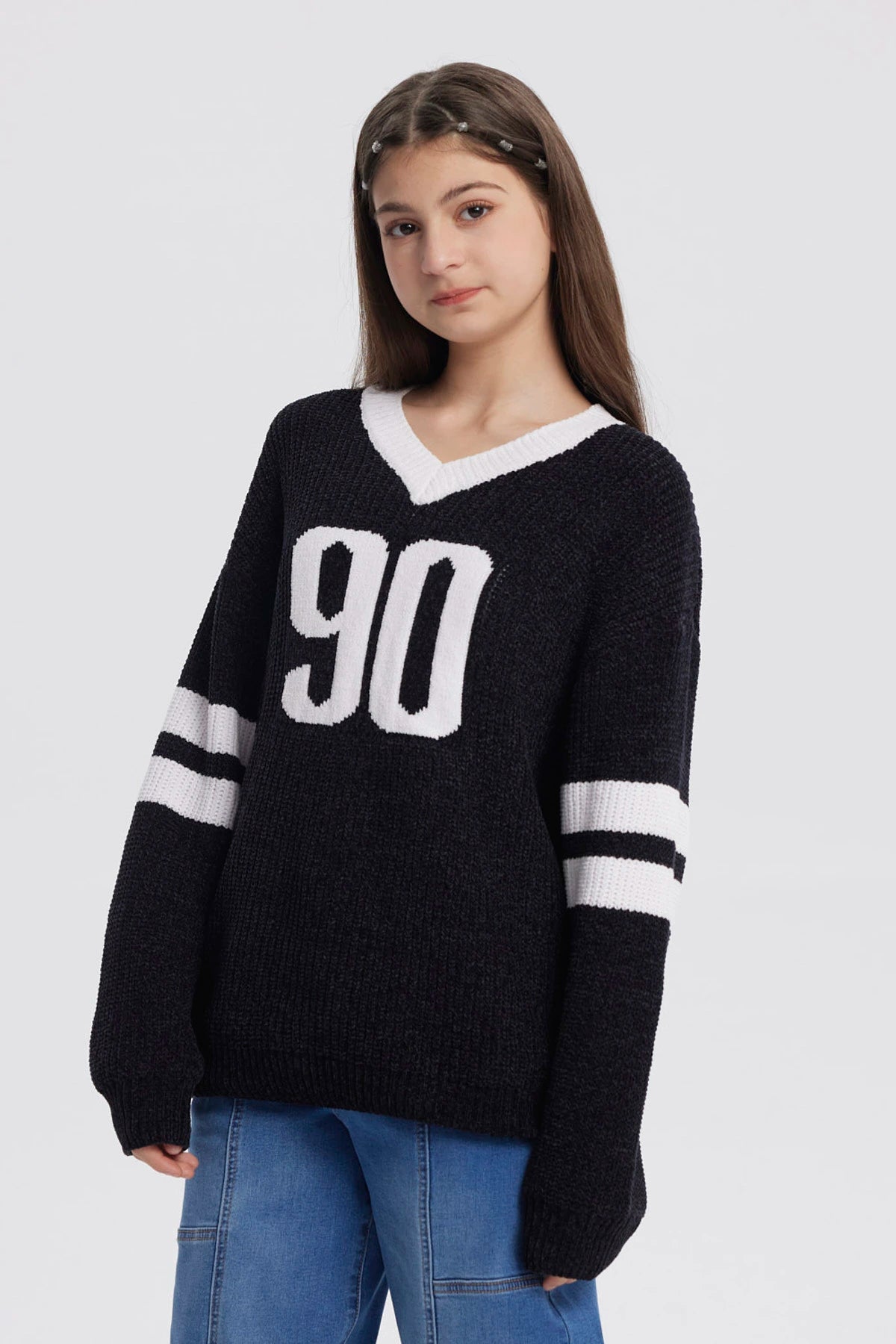 Sweater oversize negro para niña con el número 90 en blanco al frente y rayas blancas en las mangas estilo deportivo