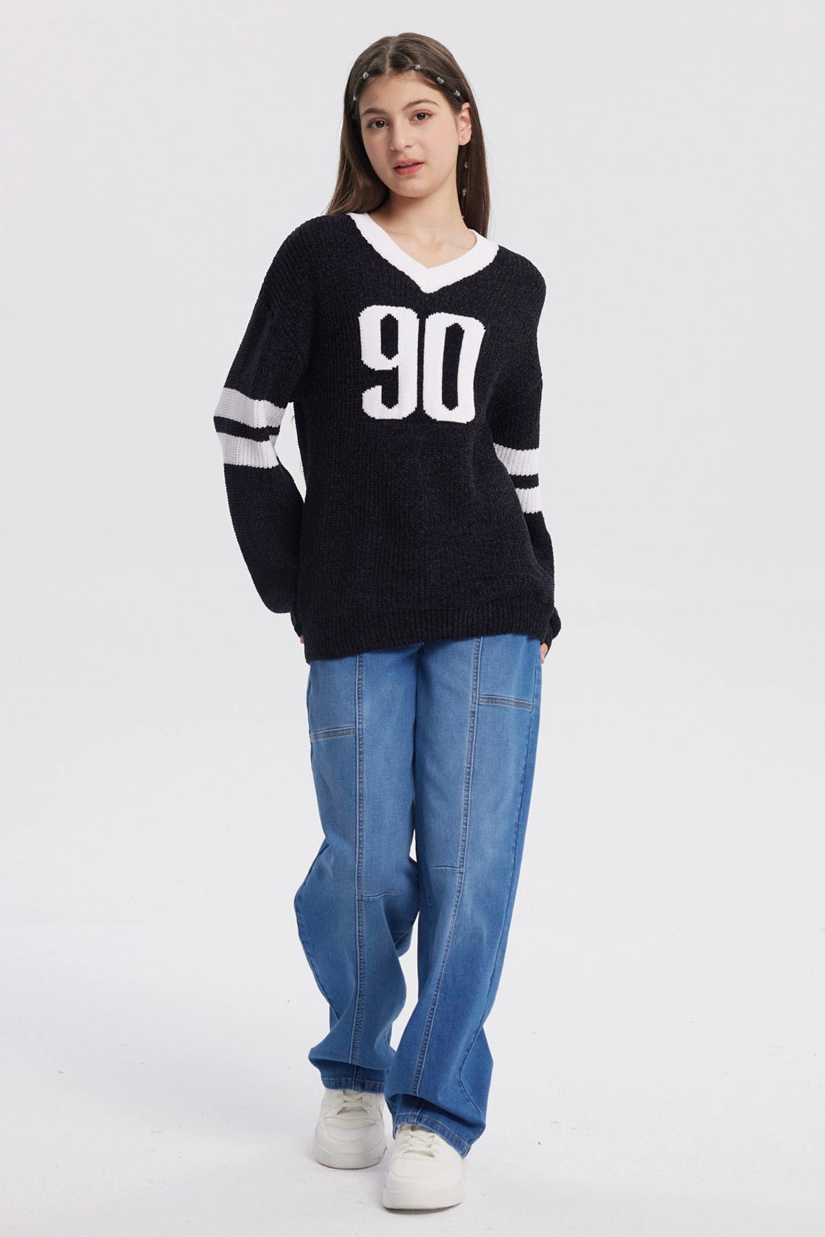 Sweater oversize negro para niña con el número 90 en blanco al frente y rayas blancas en las mangas estilo deportivo