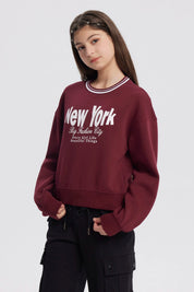 Polerón niña rojo con texto New York y diseño urbano en el frente estilo casual y relajado sin capucha