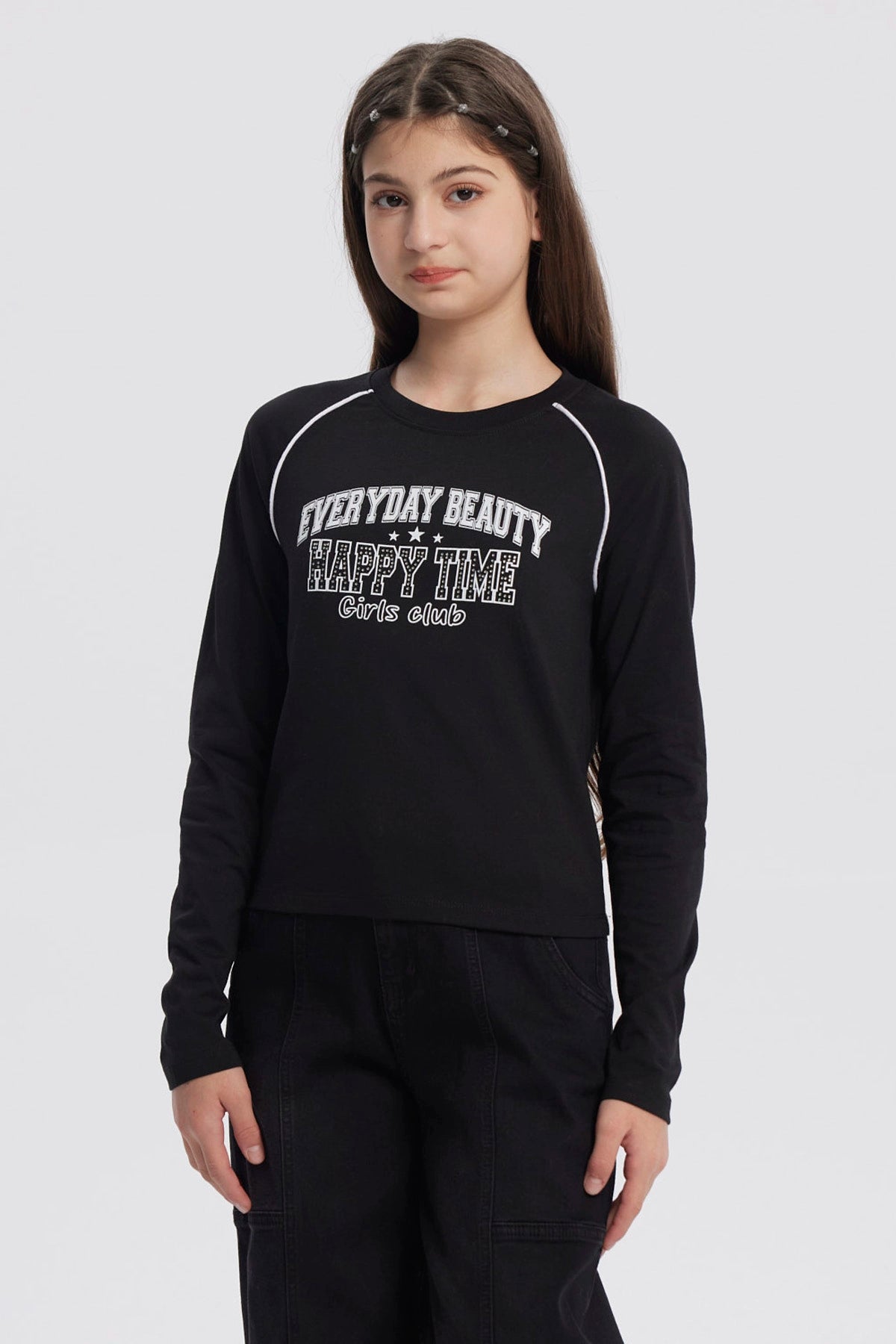Polera negra de niña con cuello redondo y texto blanco en el pecho que dice Everyday Beauty Happy Time Girls Club