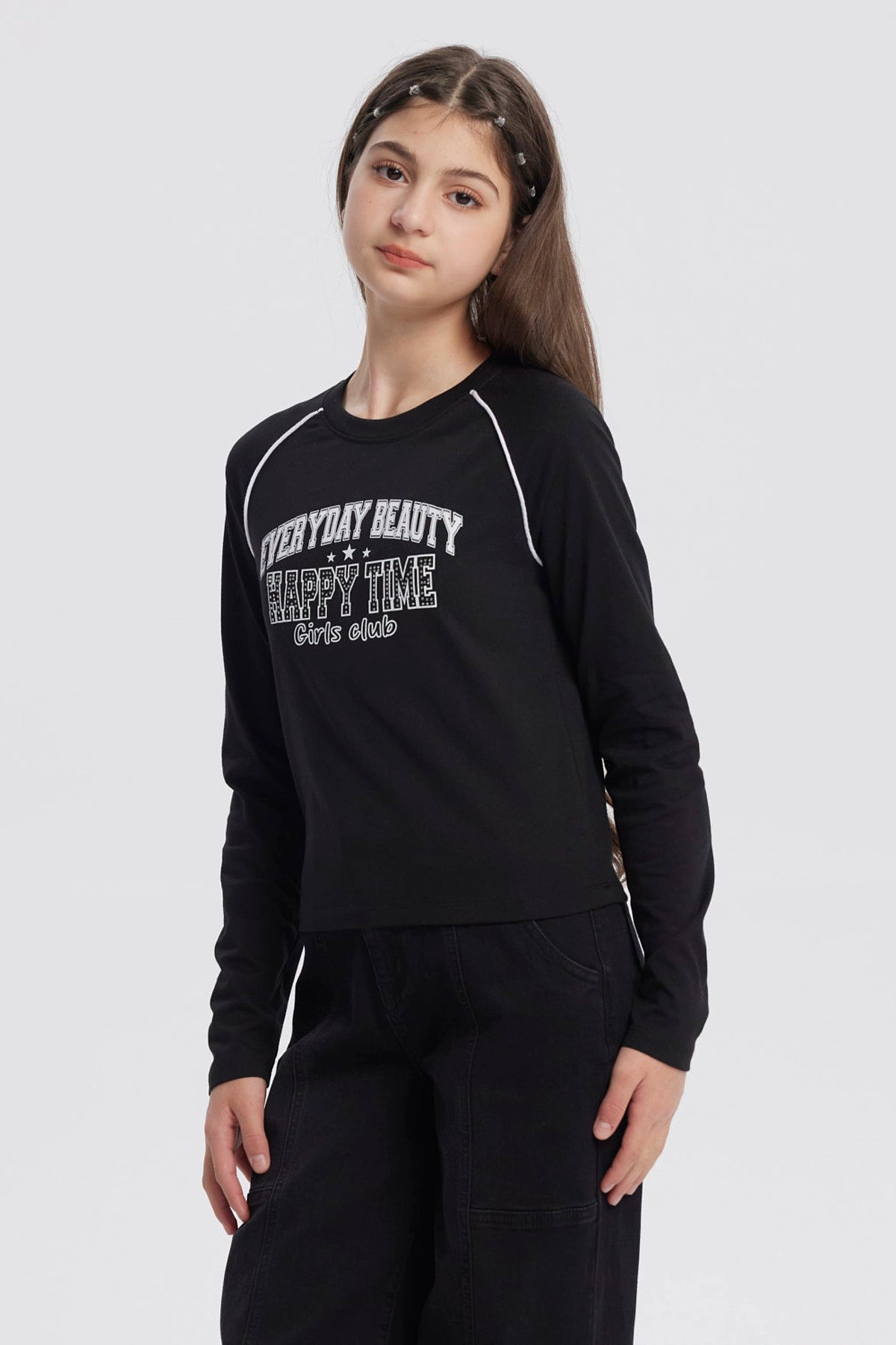 Polera negra de niña con cuello redondo y texto blanco en el pecho que dice Everyday Beauty Happy Time Girls Club