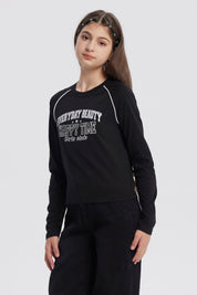 Polera negra de niña con cuello redondo y texto blanco en el pecho que dice Everyday Beauty Happy Time Girls Club