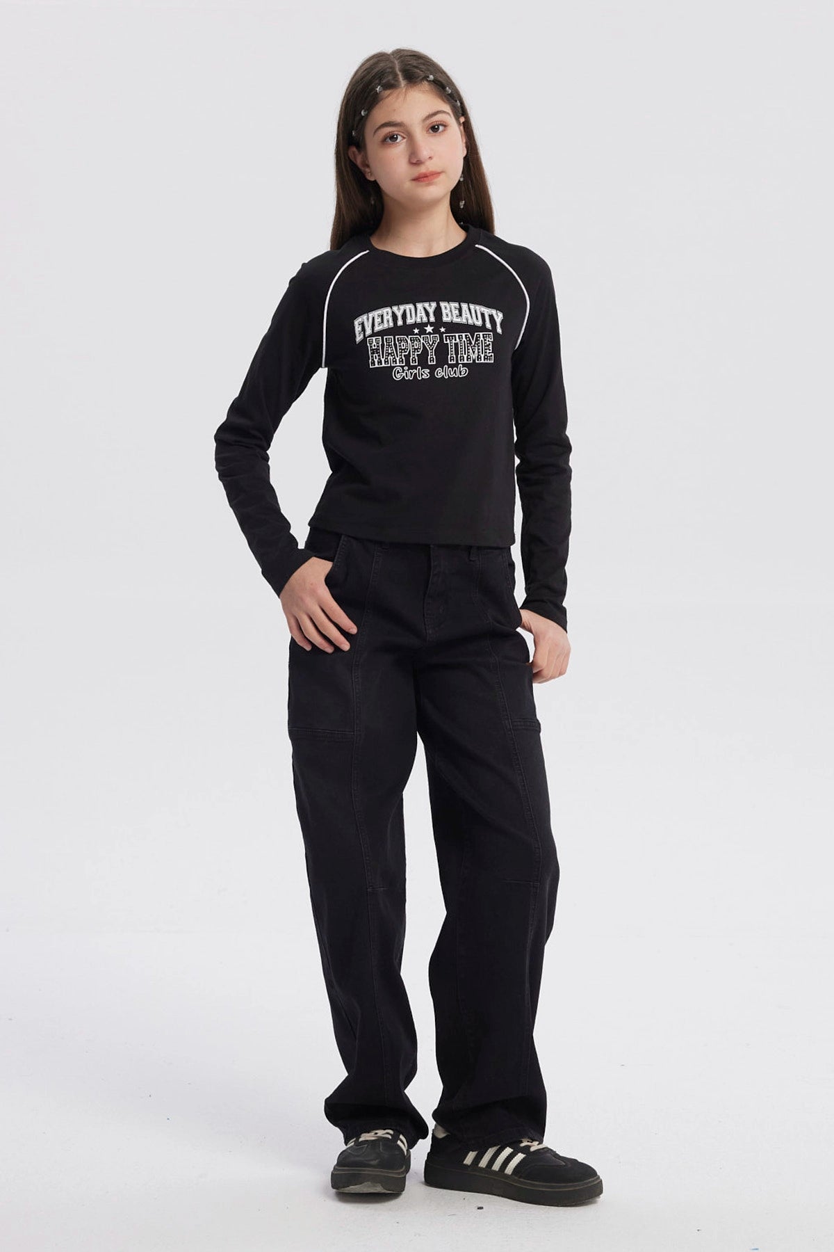 Polera negra de niña con cuello redondo y texto blanco en el pecho que dice Everyday Beauty Happy Time Girls Club