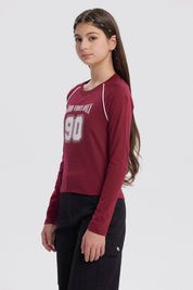 Polera niña roja con cuello redondo y texto Good Vibes Only 90 en el frente en estilo deportivo