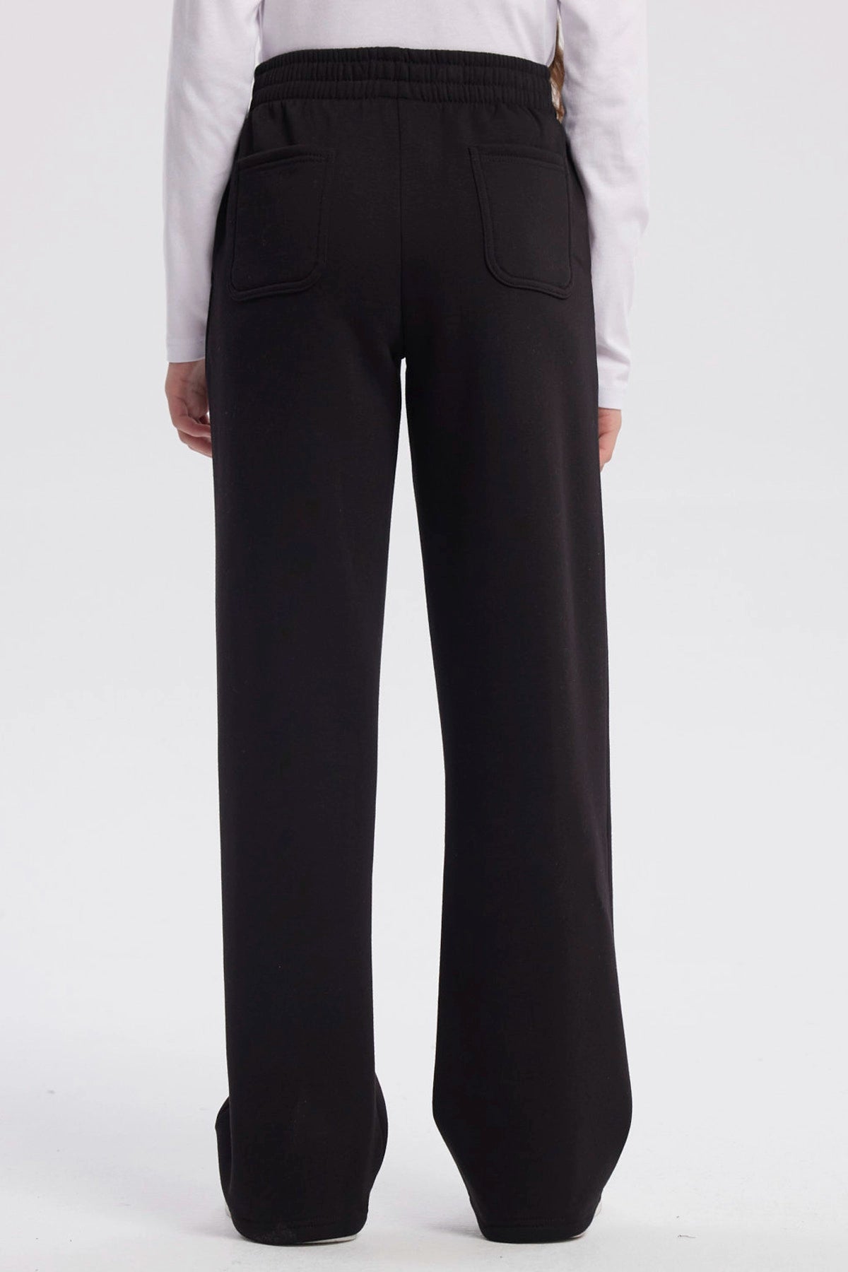 Pantalón buzo negro para niña con pierna ancha sin estampa visible diseño liso y cintura elástica para comodidad