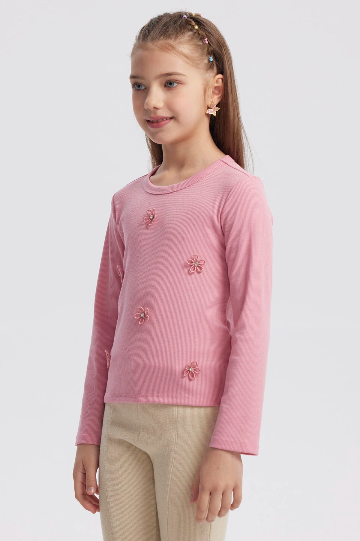 Polera slim rosada para niña con pequeñas flores bordadas en el frente diseño delicado y textura acanalada lisa