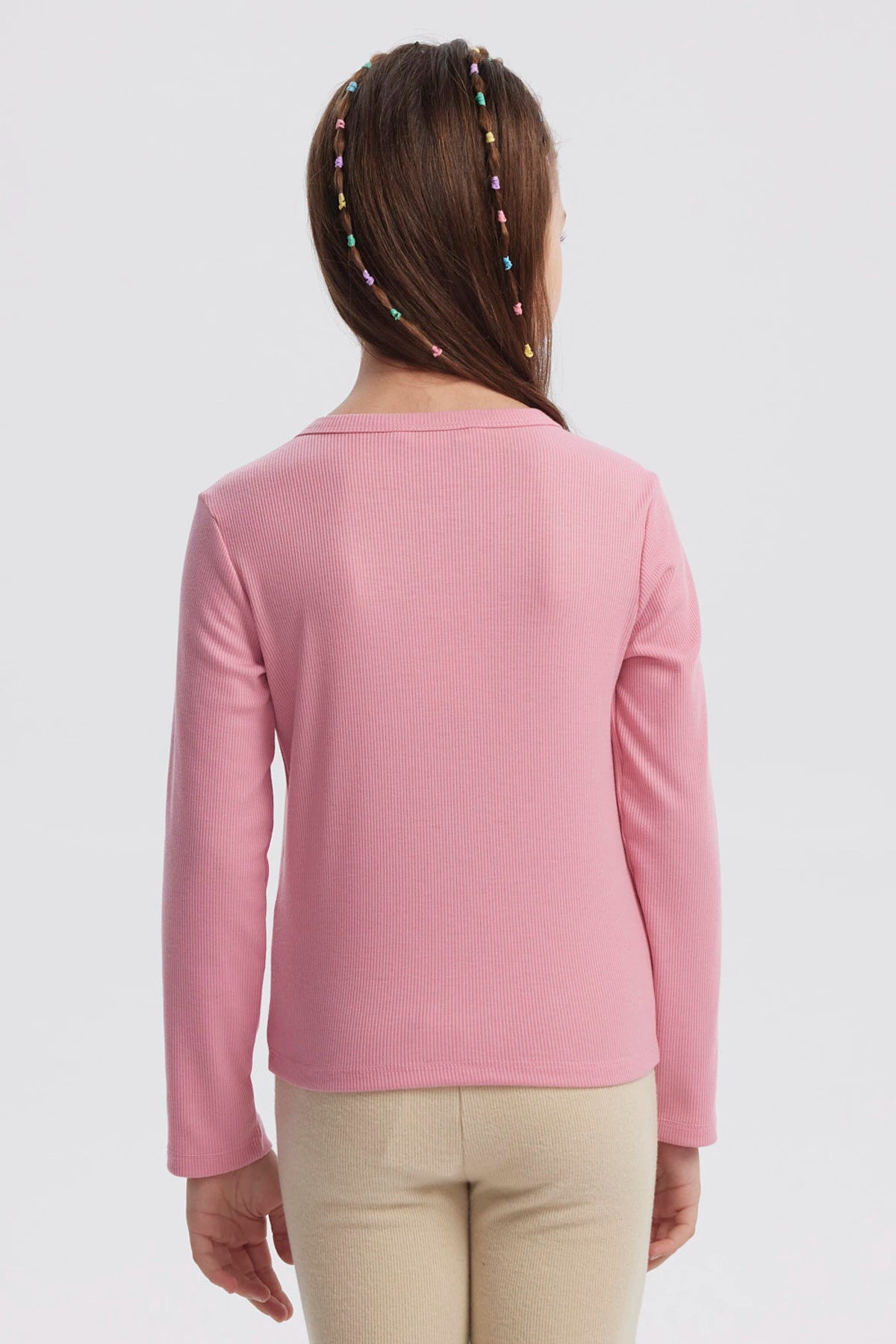 Polera slim rosada para niña con pequeñas flores bordadas en el frente diseño delicado y textura acanalada lisa