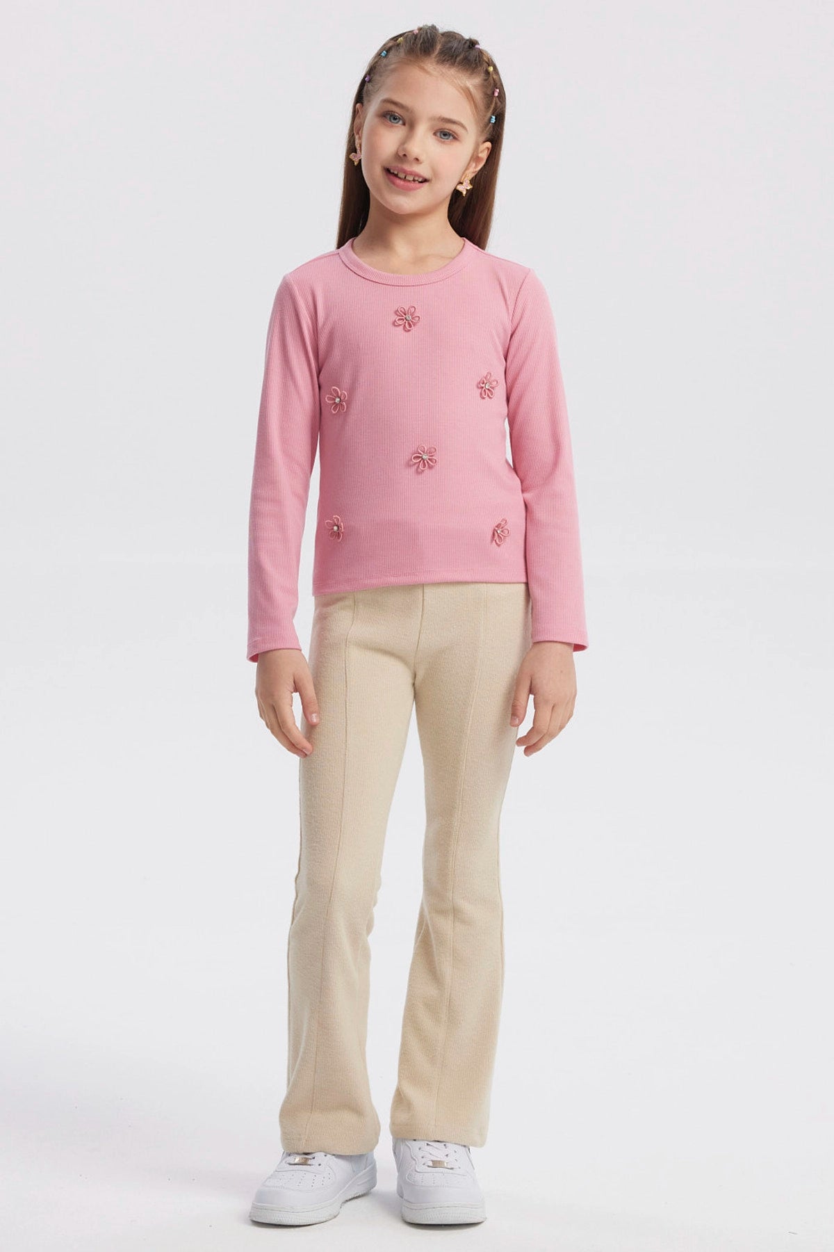 Polera slim rosada para niña con pequeñas flores bordadas en el frente diseño delicado y textura acanalada lisa