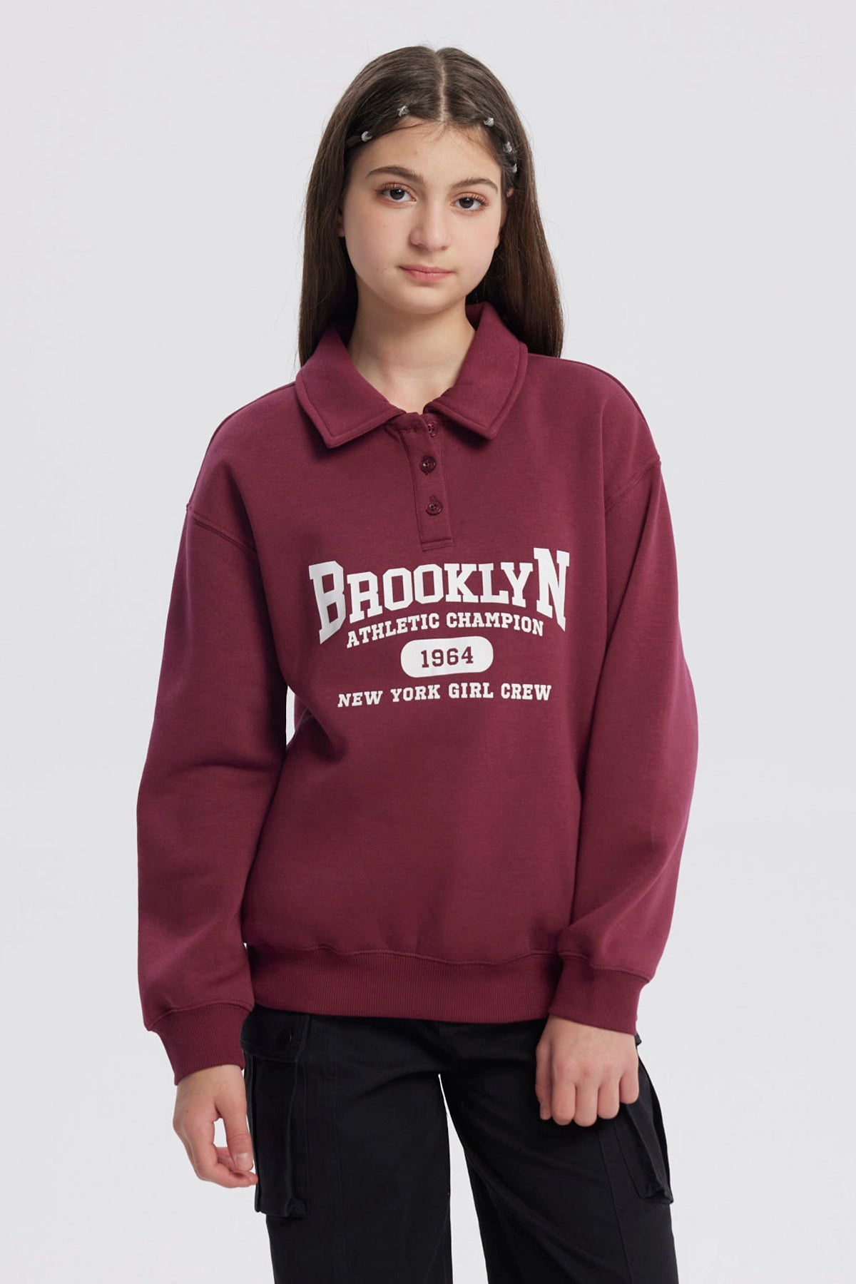 Polerón niña burdeo con cuello camisero y texto Brooklyn en el frente estilo deportivo casual