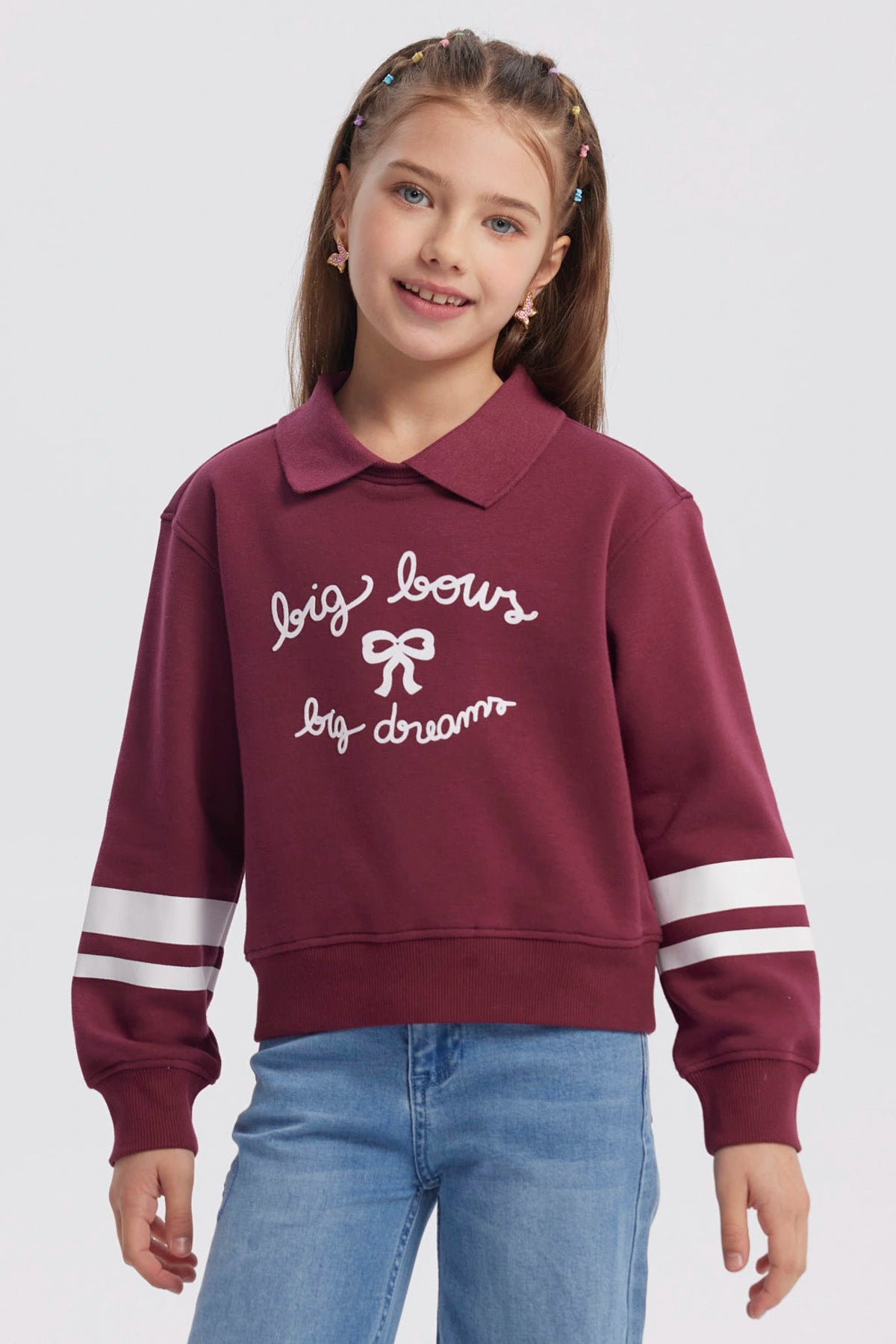 Polerón burdeo para niña con cuello camisero diseño "big bows big dreams" en el pecho y franjas blancas en las mangas