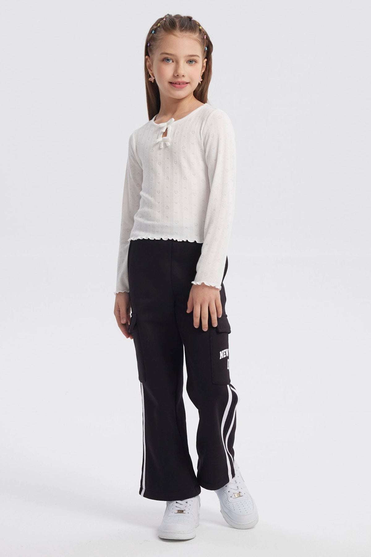 Polera crudo para niña con lazos en el cuello y detalles de corazones en patrón vertical prenda lisa y delicada