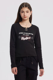 Polera negra de niña con argollas en el cuello y estampado frontal New York en letras blancas y rojas estilo urbano