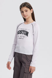 Polera crudo para niña con estampa grande de letras Boston en el centro estilo deportivo manga larga y detalles en negro