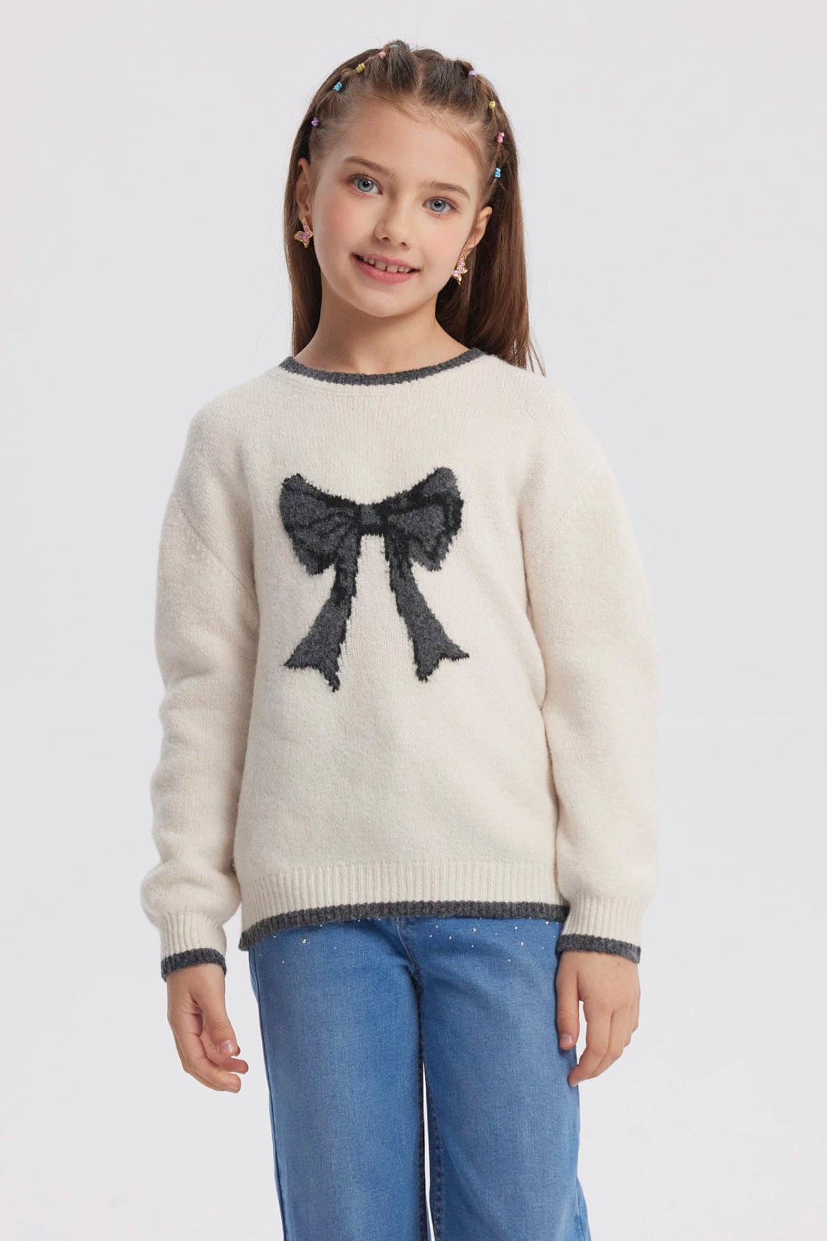 Sweater crudo para niña con moño negro grande al frente diseño gráfico contrastante manga larga y cuello redondo