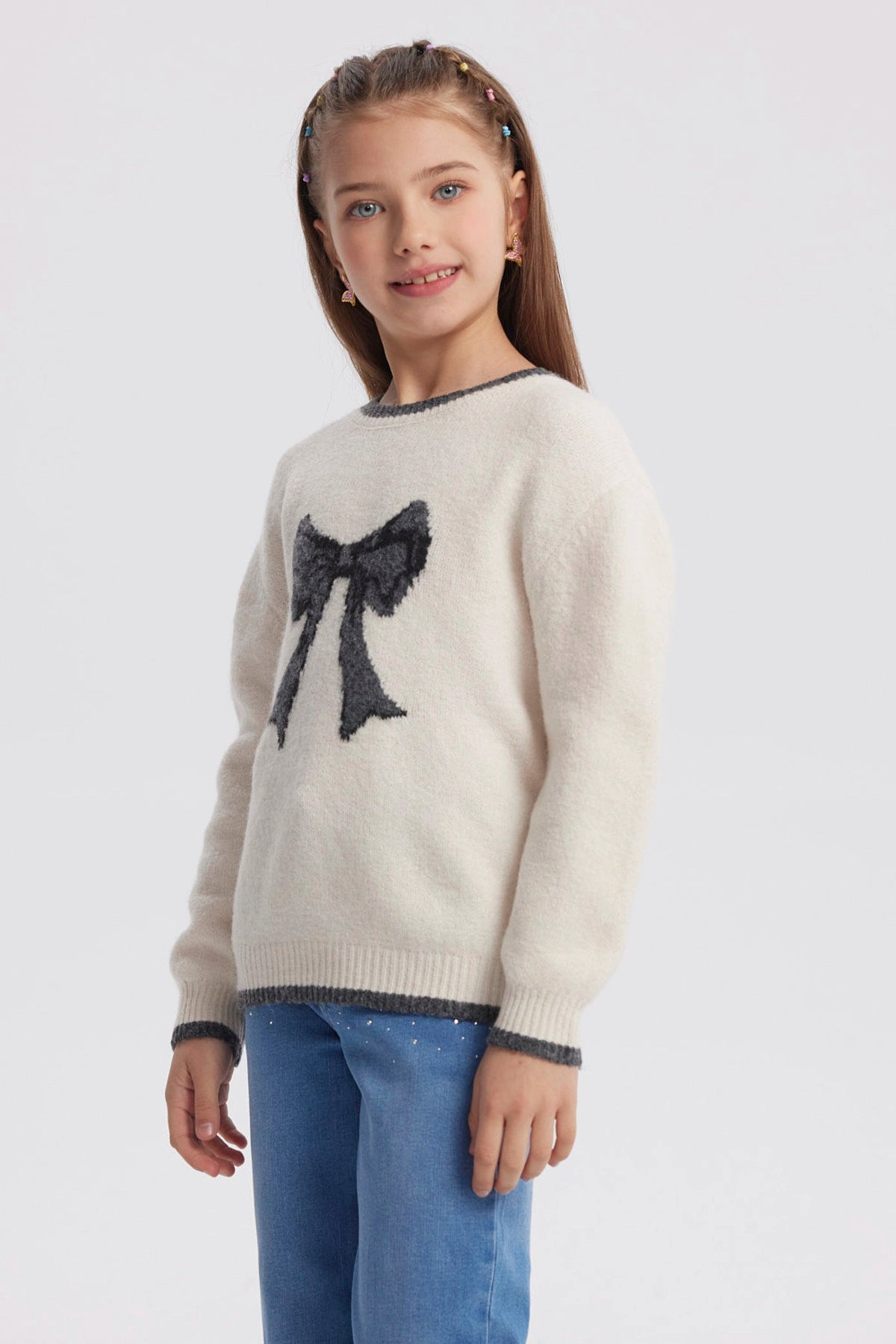 Sweater crudo para niña con moño negro grande al frente diseño gráfico contrastante manga larga y cuello redondo