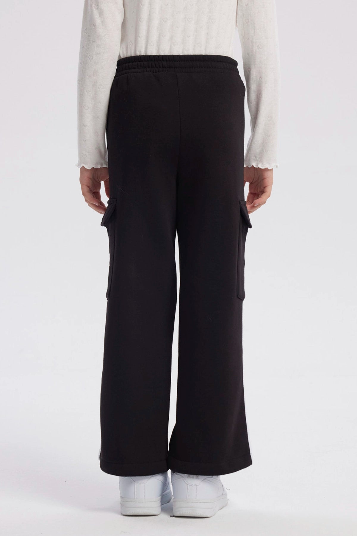 Pantalón buzo negro niña con bolsillo lateral y texto New York Dreams en la pierna estilo casual relajado