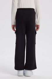 Pantalón buzo negro niña con bolsillo lateral y texto New York Dreams en la pierna estilo casual relajado