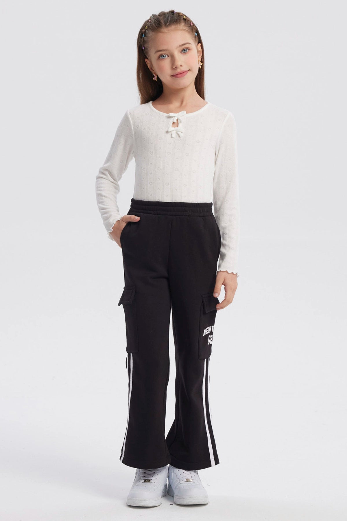 Pantalón buzo negro niña con bolsillo lateral y texto New York Dreams en la pierna estilo casual relajado