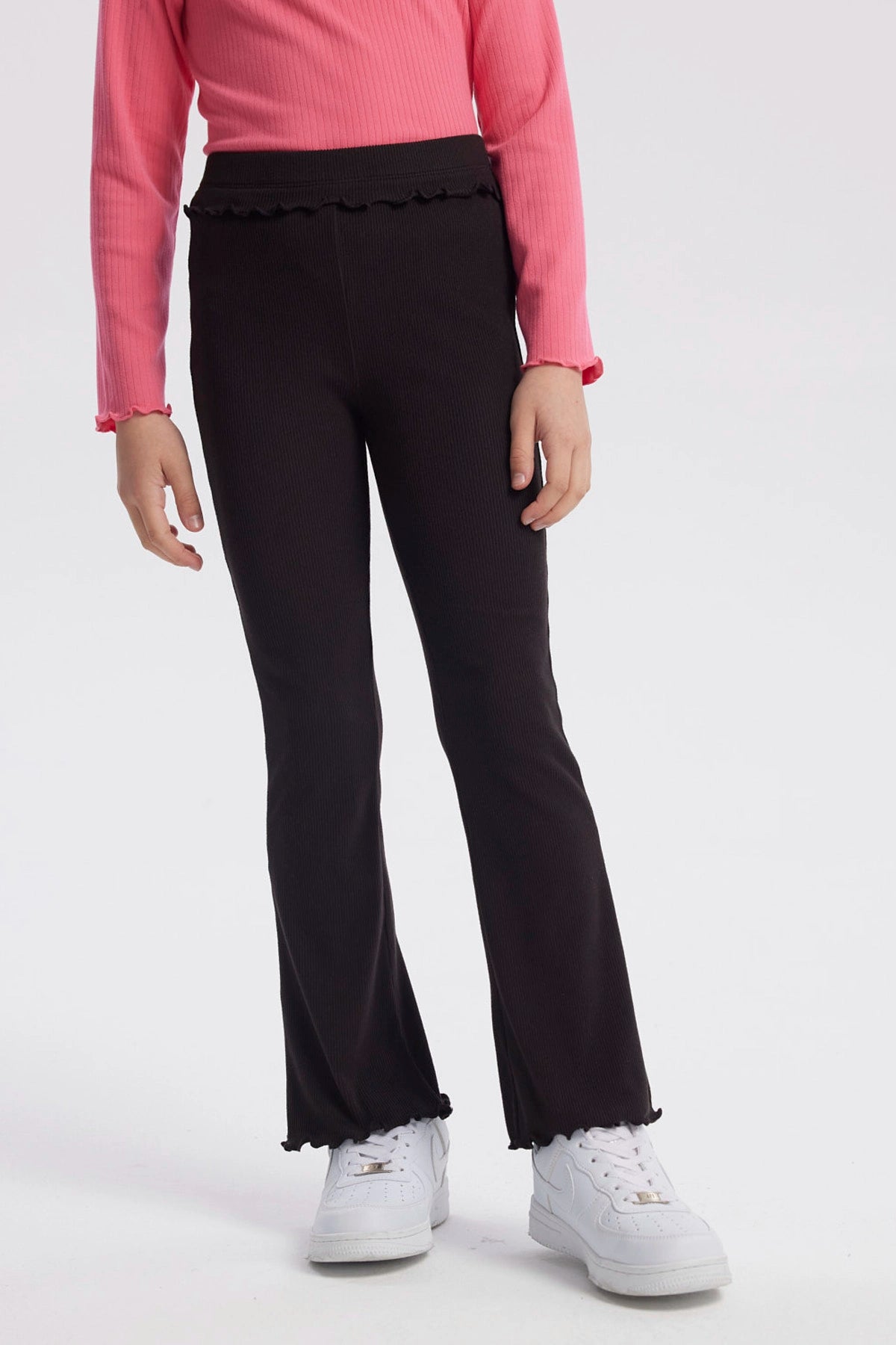 Calza flare negra para niña con textura acanalada y borde ondulado en cintura y tobillos diseño liso