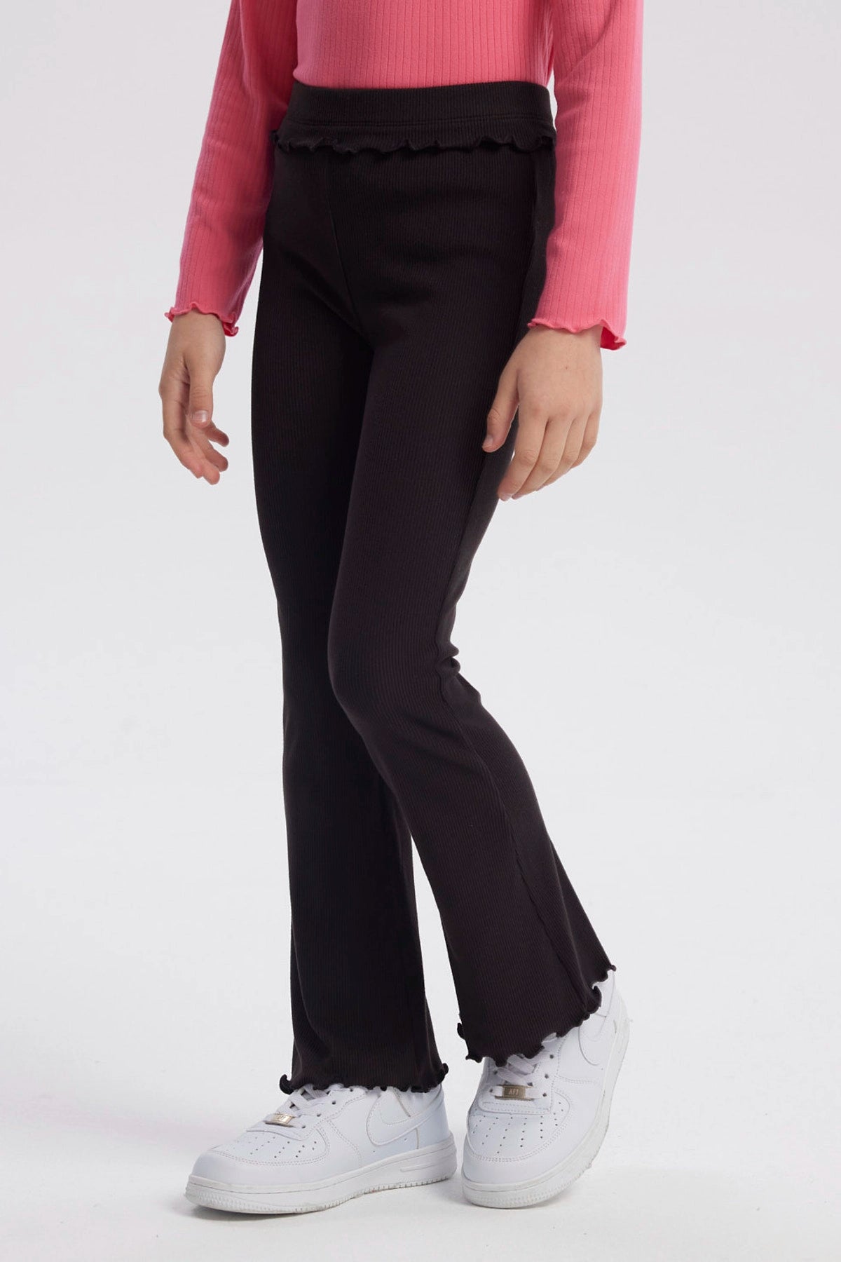 Calza flare negra para niña con textura acanalada y borde ondulado en cintura y tobillos diseño liso