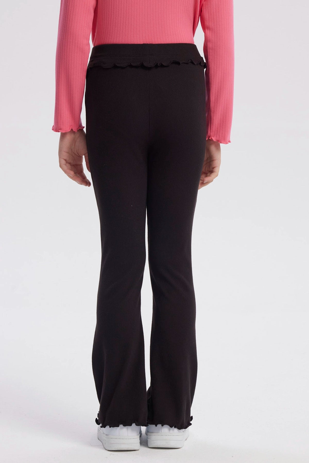 Calza flare negra para niña con textura acanalada y borde ondulado en cintura y tobillos diseño liso