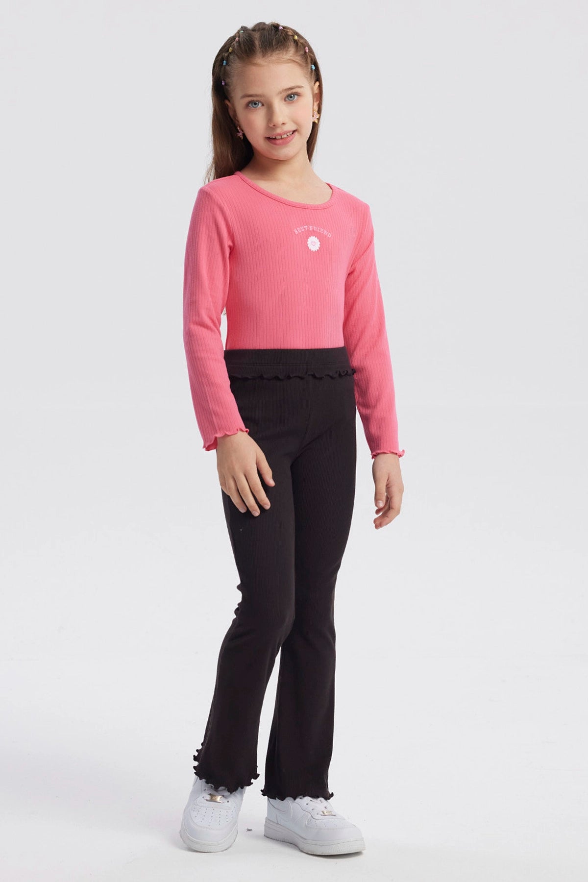 Calza flare negra para niña con textura acanalada y borde ondulado en cintura y tobillos diseño liso