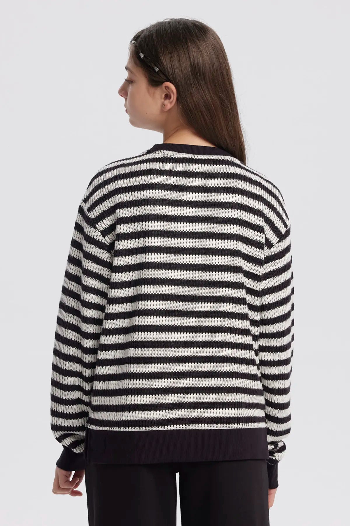 Polerón niña cuello redondo negro con rayas horizontales blancas diseño casual y relajado sin estampa visible