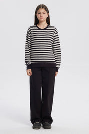 Polerón niña cuello redondo negro con rayas horizontales blancas diseño casual y relajado sin estampa visible