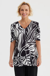 Polera negra de mujer con estampado blanco de hojas abstractas estilo gráfico en toda la prenda
