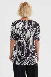 Polera negra de mujer con estampado blanco de hojas abstractas estilo gráfico en toda la prenda