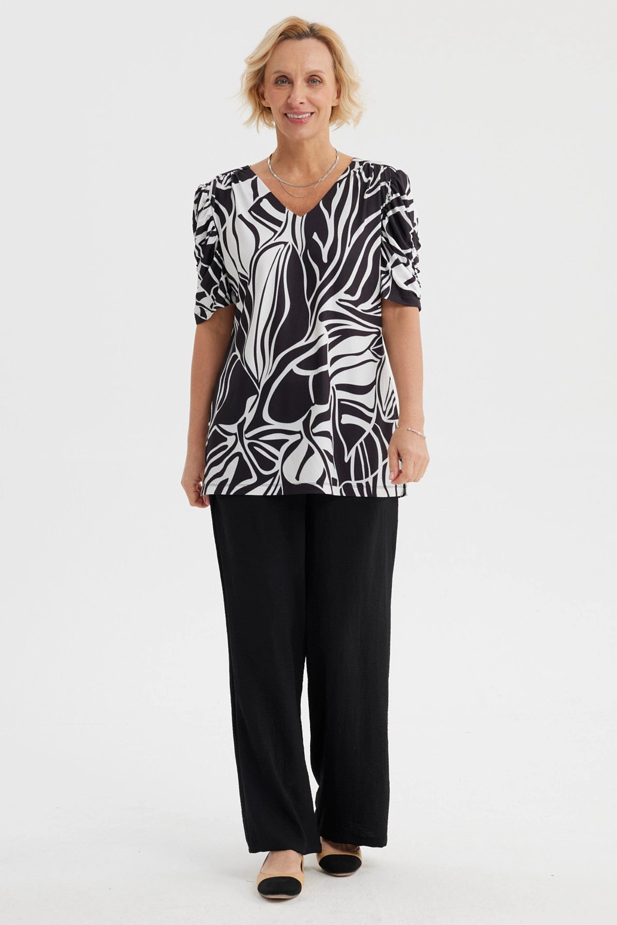 Polera negra de mujer con estampado blanco de hojas abstractas estilo gráfico en toda la prenda
