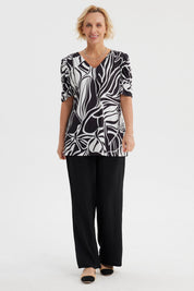 Polera negra de mujer con estampado blanco de hojas abstractas estilo gráfico en toda la prenda
