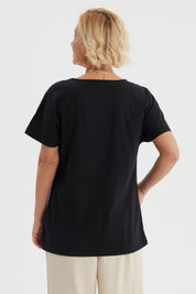 Polera mujer cuello bote negra con estampado de líneas brillantes en el pecho estilo floral gráfico elegante