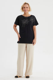 Polera mujer cuello bote negra con estampado de líneas brillantes en el pecho estilo floral gráfico elegante