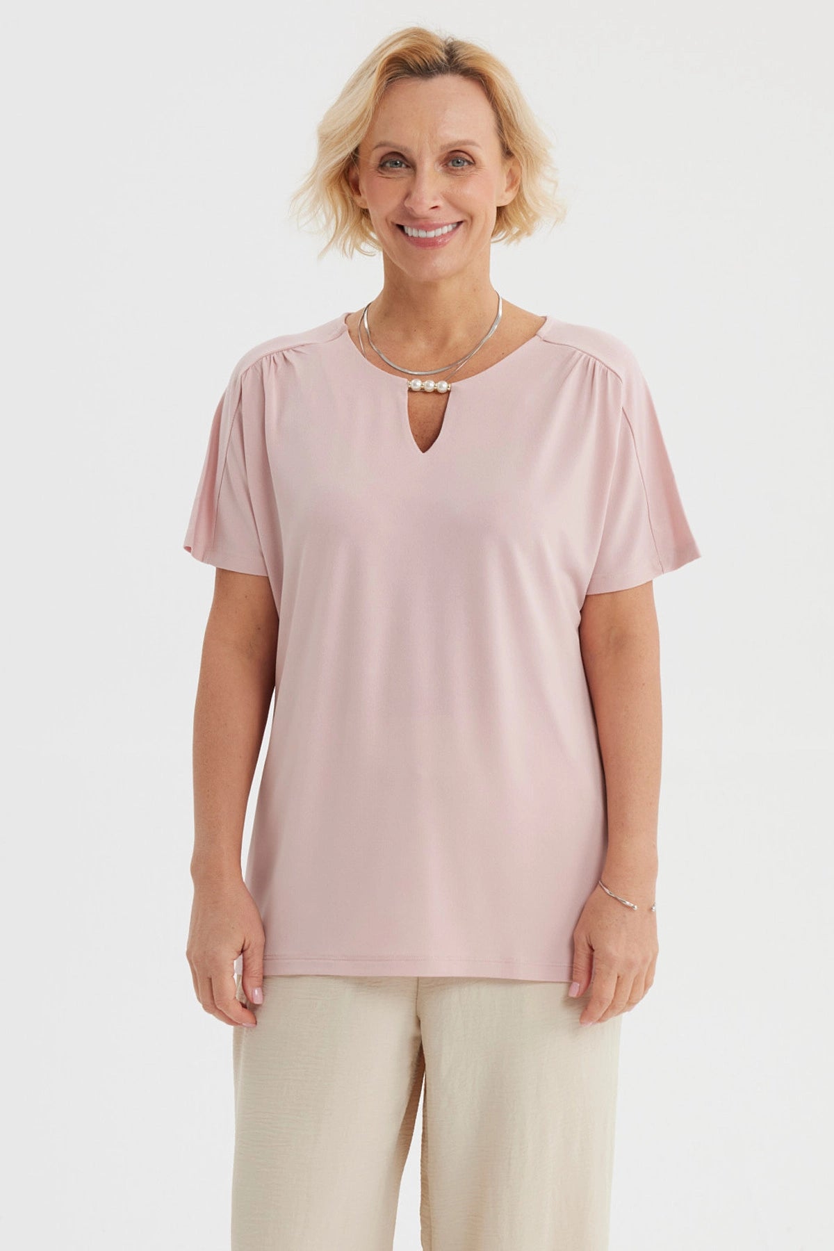 Polera rosada para mujer con detalle de perlas en el escote y diseño liso de manga corta