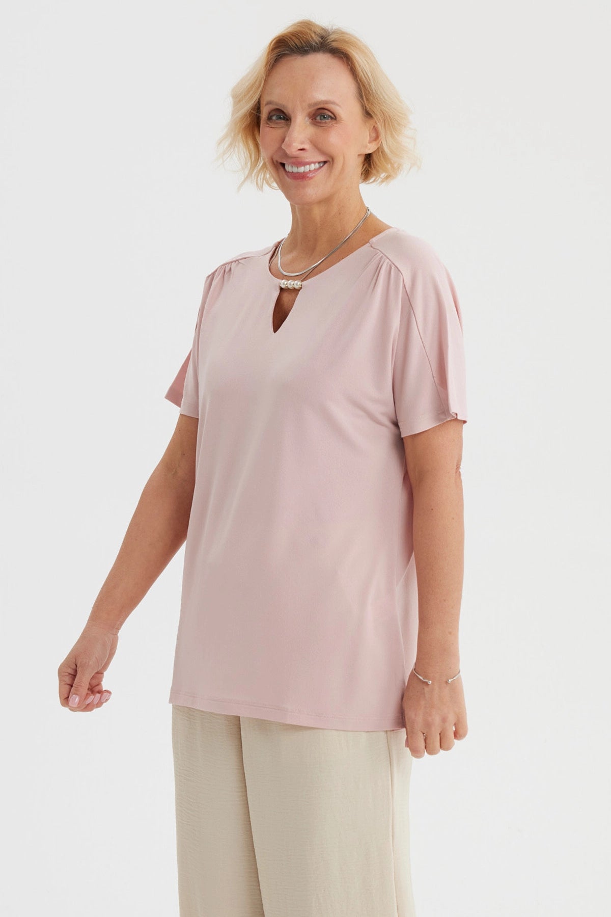 Polera rosada para mujer con detalle de perlas en el escote y diseño liso de manga corta