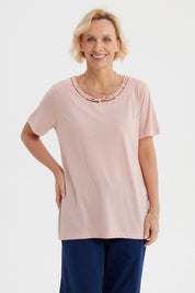Polera de mujer rosada con detalle decorativo en el cuello lisa de manga corta y corte recto