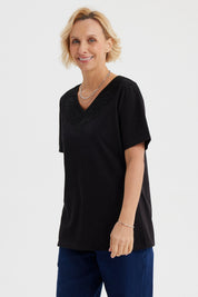 Polera negra de mujer con detalle de macramé en el escote en forma de V diseño elegante y sin estampa visible