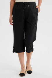 Pantalón pescador negro con cortes y aperturas detalles en la parte inferior liso con cintura elástica y bolsillos delanteros