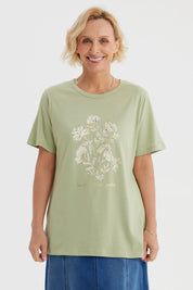 Polera verde claro con estampado de flores blancas y texto La vie est un jardin al frente