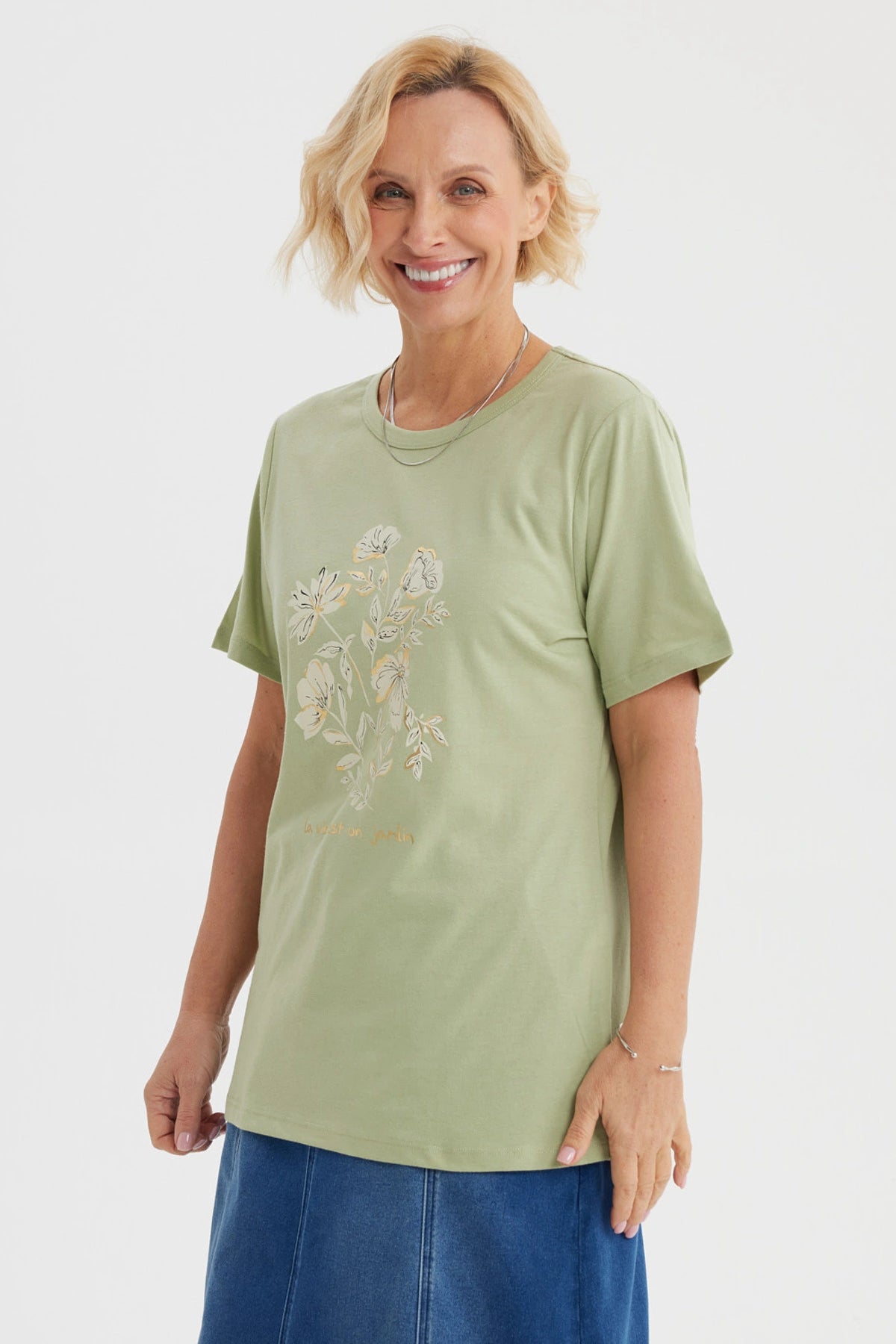 Polera verde claro con estampado de flores blancas y texto La vie est un jardin al frente