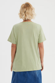 Polera verde claro con estampado de flores blancas y texto La vie est un jardin al frente
