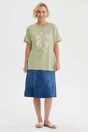 Polera verde claro con estampado de flores blancas y texto La vie est un jardin al frente